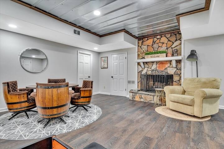 Game room with a stone fireplace and barrel-style table seating