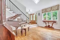 Open entry hall with piano, staircase, and natural light