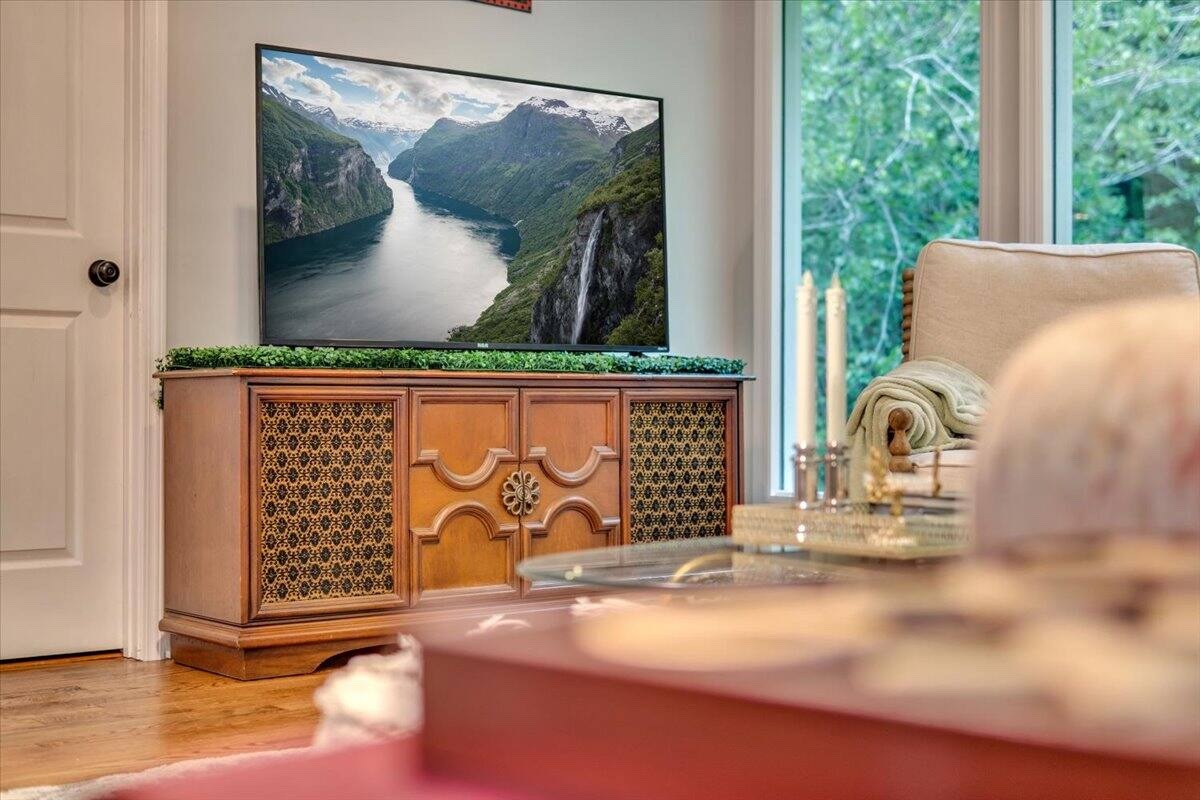 Comfortable lounge area with a large television and wooded view
